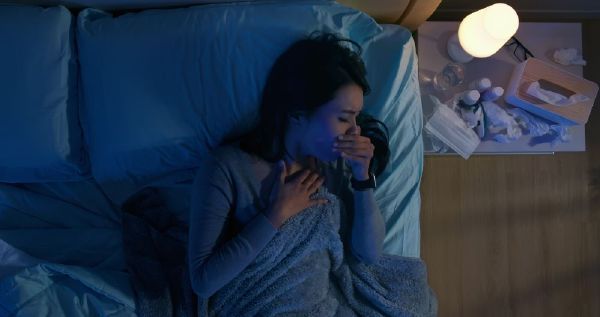 Donna sotto le coperte che soffre a causa della tosse secca notturna